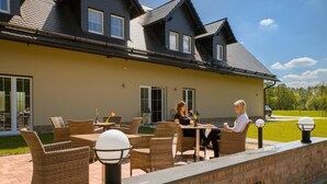 A house with a patio area featuring wicker furniture and outdoor lighting.