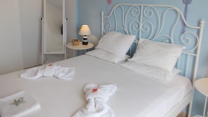Un lit avec du linge de lit blanc, deux oreillers, une table de chevet avec une lampe et un petit objet décoratif accroché au mur.