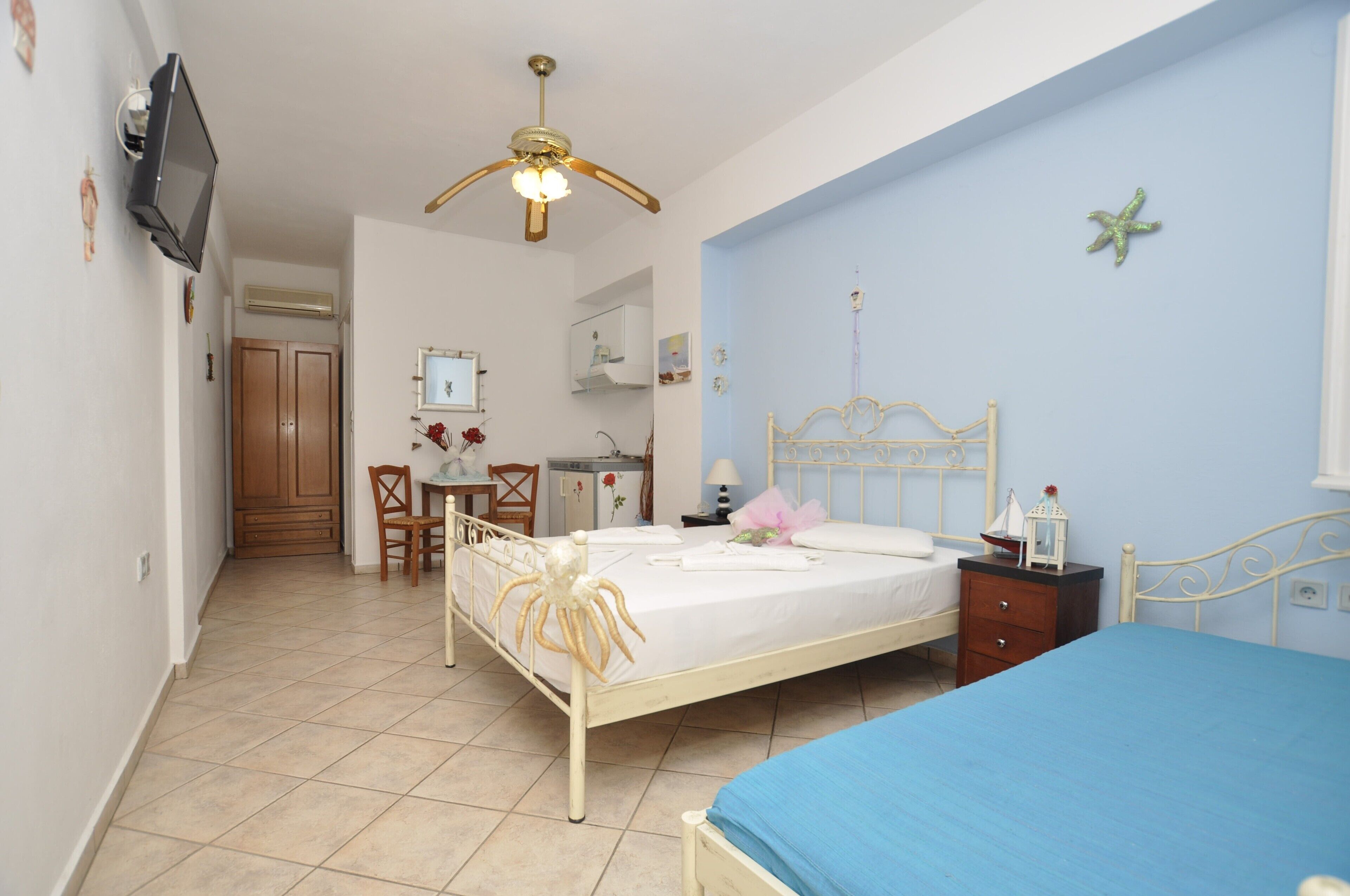 A bedroom with a bed, a desk, a chair, a wardrobe, and a ceiling fan.