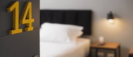 Ein Hotelzimmer mit einem Bett, einem Nachttisch und einer Wandtafel mit der Nummer 14.