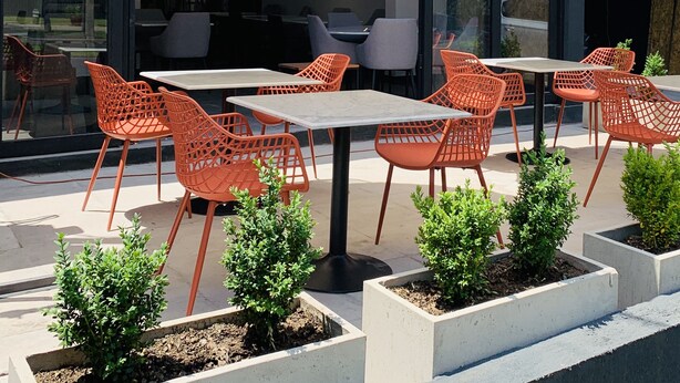 Outdoor seating with tables and chairs, umbrellas, and small potted plants. - The Pop Hotels (Santiago)