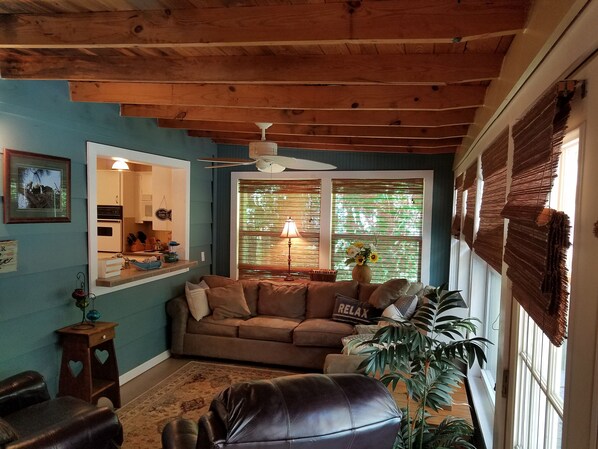 A cozy living room with a wooden ceiling, a sofa, a coffee table, and a large window with blinds. - Summer Openings! Perfect spot on lake for fishing! Spacious home & backyard (Iuka)