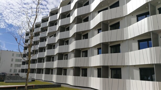 Un edificio moderno a più piani con facciata uniforme, balconi e ampie finestre.