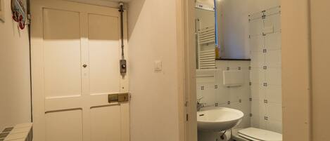 A bathroom with a white door, a sink, and a toilet.