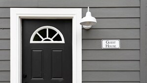 A black door with a white-framed window and a 'Guest House' sign on a grey wooden wall. - Lyric Guesthouse at GratiDude Ranch - Riverside in Leiper's Fork (Franklin)