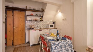 Una cocina compacta con microondas, estantes con frascos y una zona de comedor con una mesa para dos.