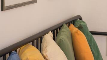 A bed with a black metal frame and colorful pillows in various shades.