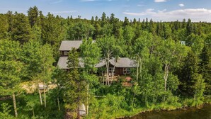 Une cabane entourée d’une forêt dense, offrant une vue dégagée sur les arbres environnants et une rivière.