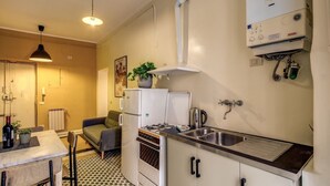 A compact kitchen with a gas stove, a refrigerator, a sink, and a radiator. - Trastevere Vintage (Rome)