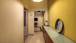 A hallway with a glass-top desk, a round mirror, and a ceiling light. - Trastevere Vintage (Rome)