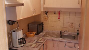 A compact kitchen with a stove, microwave, toaster, and sink.