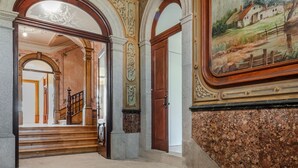 A grand staircase with ornate railings and a mural depicting a rural landscape. - Menina Colina Guesthouse (Porto)