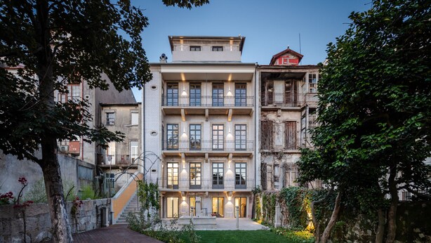 A multi-story building with a courtyard, featuring a staircase, a wooden deck, and a well-maintained garden. - Menina Colina Guesthouse (Porto)