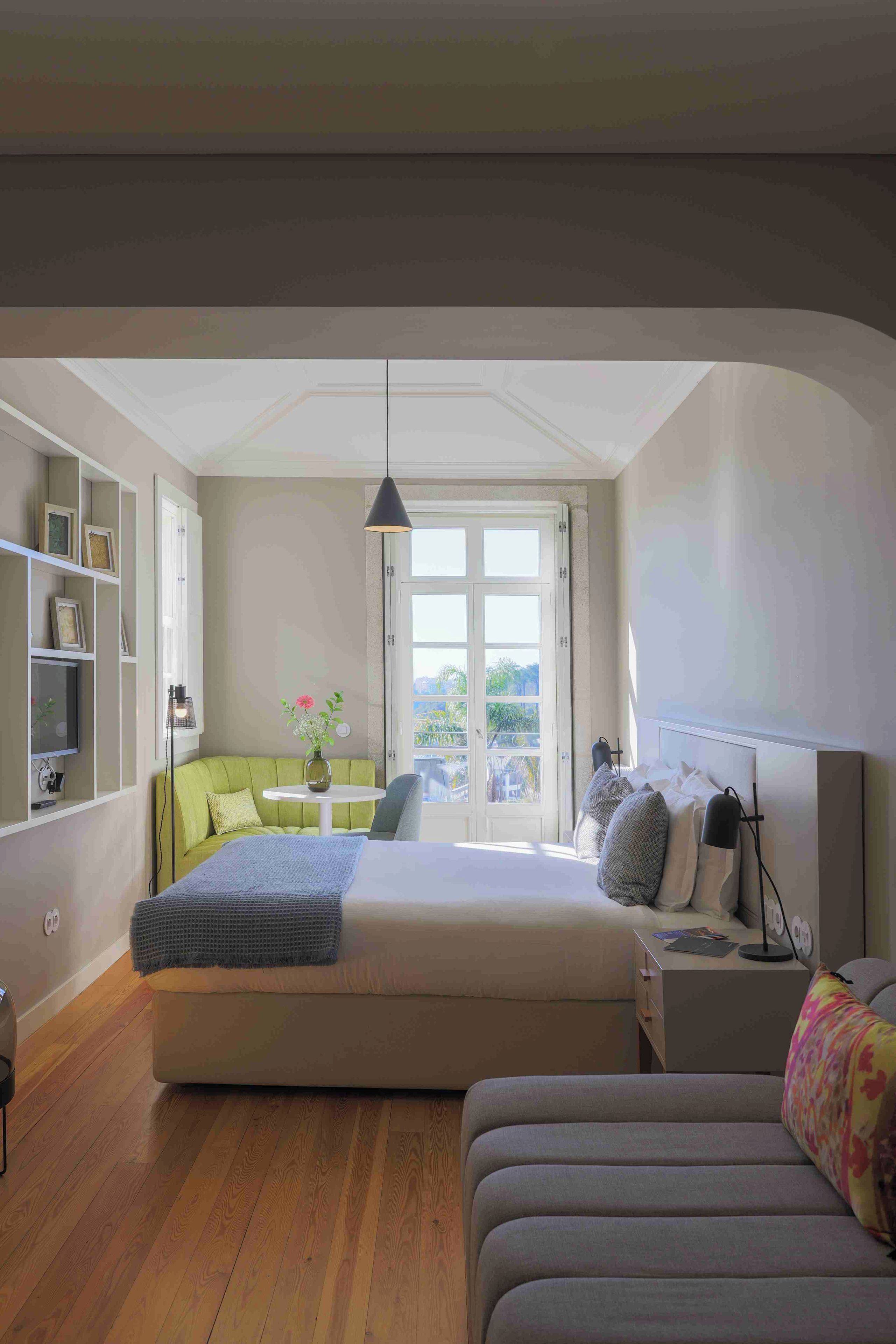 Ein modernes Schlafzimmer mit Bett, Sofa, Schreibtisch und einem Balkon.