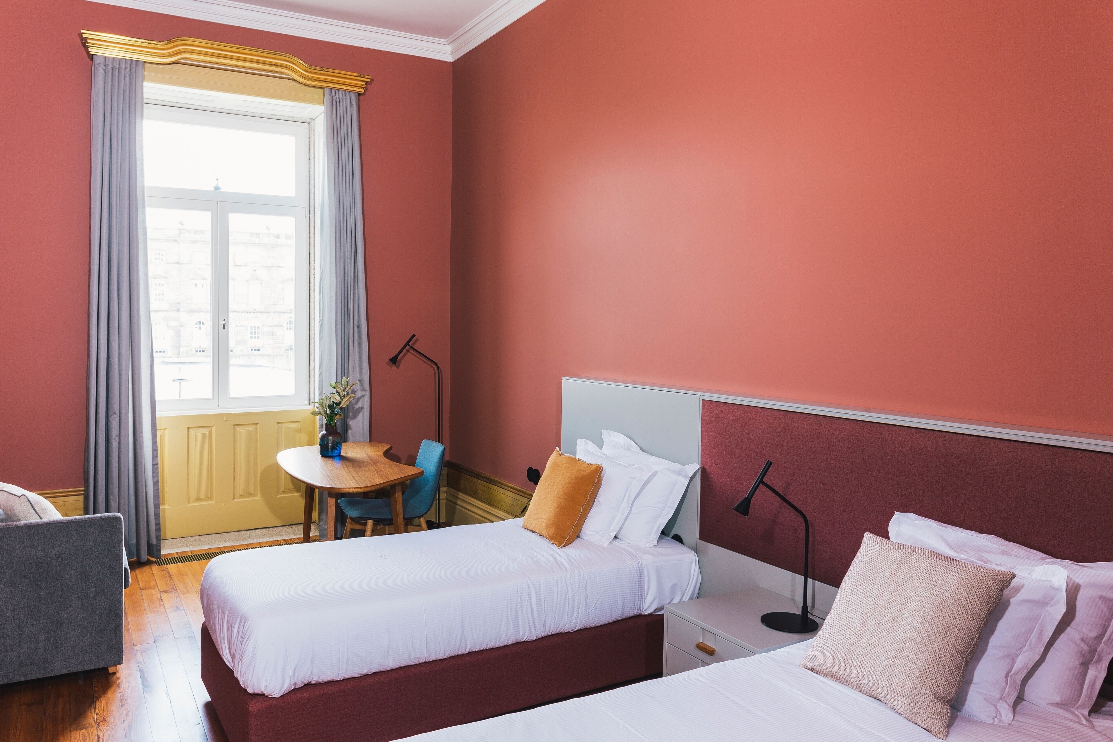Una habitación de hotel con dos camas, una mesa de comedor y una ventana con cortinas.