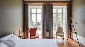 A hotel room with a large bed, two chairs, a tripod, and a window with curtains. - Menina Colina Guesthouse (Porto)