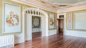 A spacious room with ornate ceiling details, a large mirror, and classical wall paintings. - Menina Colina Guesthouse (Porto)