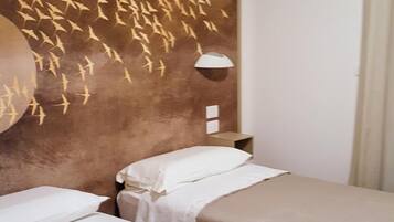 Una camera d'albergo con due letti, una lampada a parete e un elemento decorativo.