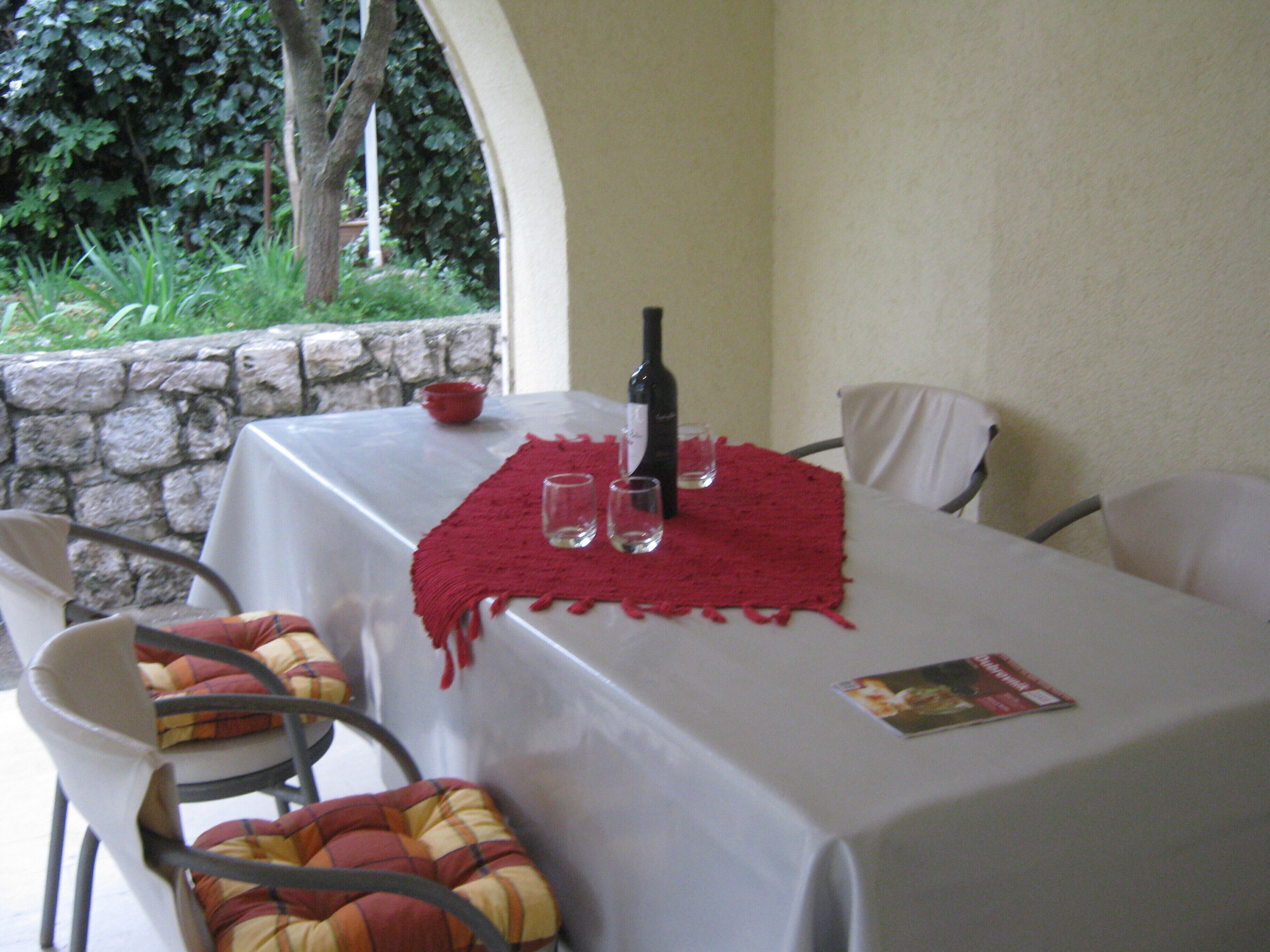 A table set for two with a red placemat, a bottle of wine, and two glasses.