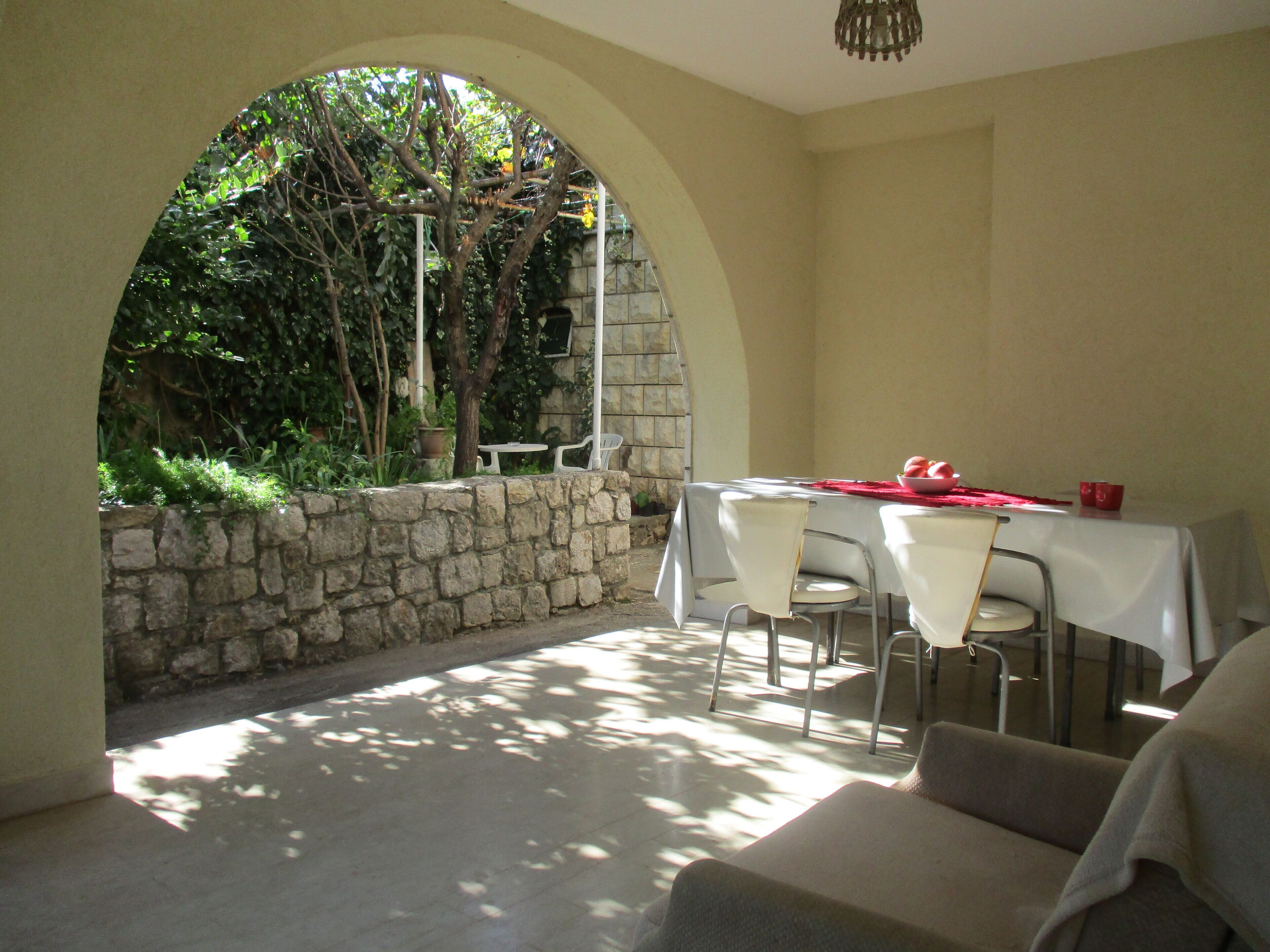 A dining area with a stone wall, a table with chairs, and a view of greenery.