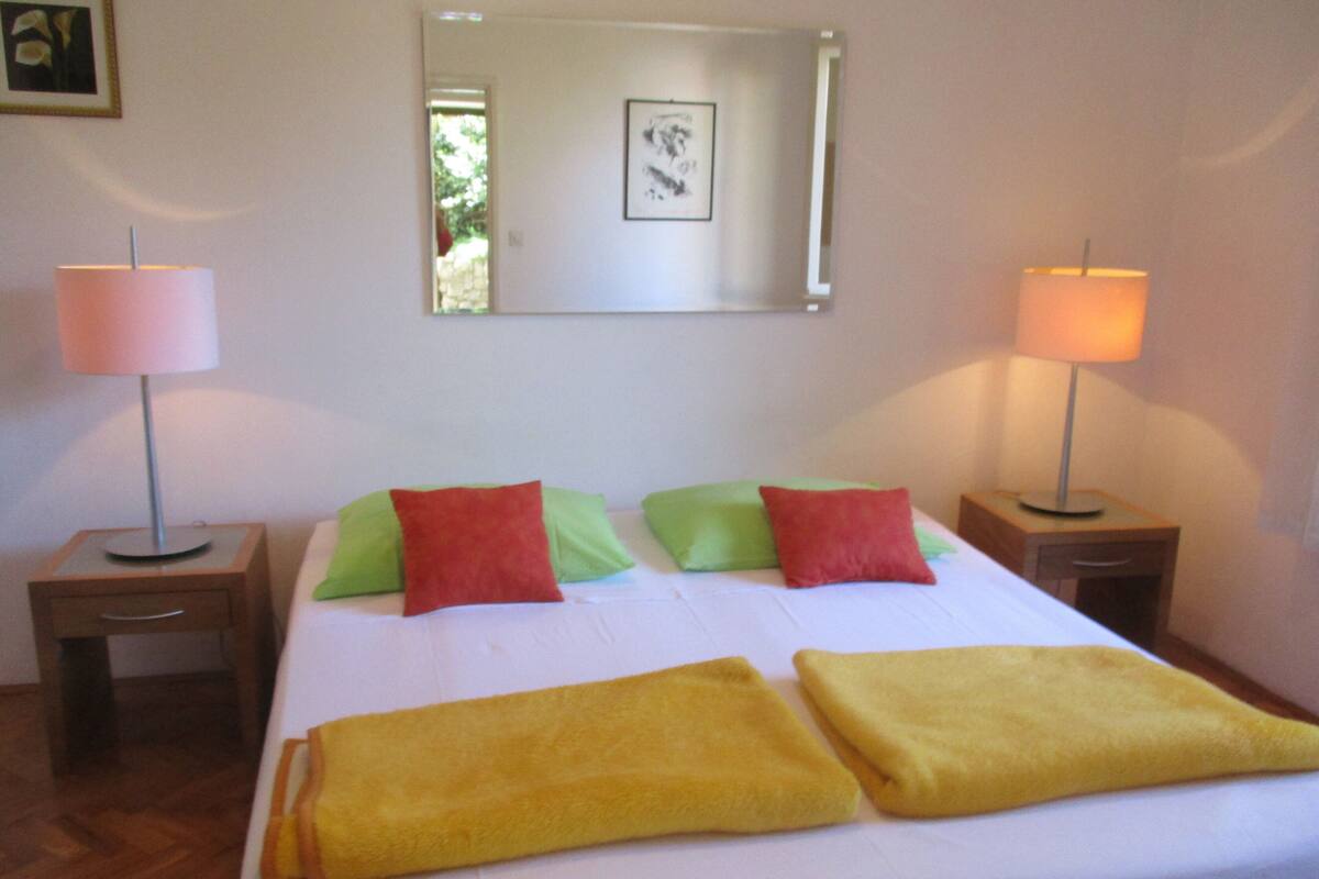 A hotel room with a bed, two bedside tables, two lamps, and a mirror on the wall.
