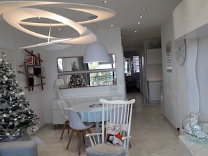 Una cocina moderna con comedor, un árbol de Navidad y una lámpara contemporánea.