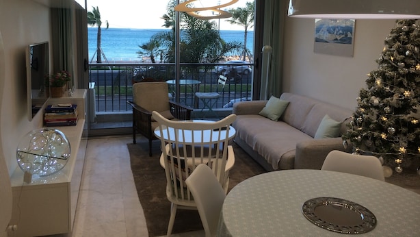 A modern living room with a balcony overlooking the ocean, a Christmas tree, and a dining area with a round table. -  CHARMING APARTMENT ON THE BEAUTIFUL PROMENADE OF ENGLISH FACING THE SEA AND BEACHES (Nice)