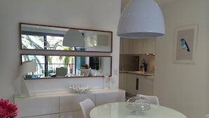 A modern kitchen with white cabinetry, a round glass table, and white chairs. -  CHARMING APARTMENT ON THE BEAUTIFUL PROMENADE OF ENGLISH FACING THE SEA AND BEACHES (Nice)