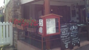 A restaurant with a sign reading "BAR - RESTAURANT CITED'ETAPE ZUHARPETA" and a phone number. There is a small outdoor seating area with a number 5 sign and a menu board. - Gite Zuharpeta Randonneurs Pèlerins - Hostel (Saint-Jean-Pied-de-Port)