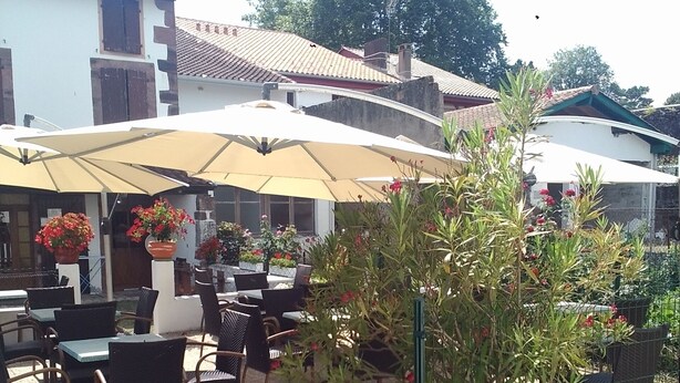 An outdoor patio area with tables and chairs, umbrellas, and potted plants. - Gite Zuharpeta Randonneurs Pèlerins - Hostel (Saint-Jean-Pied-de-Port)