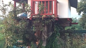 A treehouse with a red railing and a horse statue on top. - La Coquille Napoléon (Uhart-Cize)