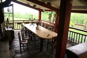 A wooden deck with a long table and chairs, overlooking a green landscape. - La Coquille Napoléon (Uhart-Cize)
