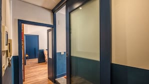 A hallway with wooden flooring, a blue door, and a glass partition. - Trastevere Vintage 2 (Rome)