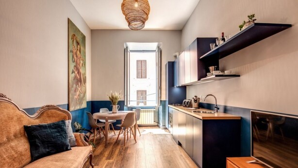 A compact living space with a sofa, dining table, and kitchenette. - Trastevere Vintage 2 (Rome)