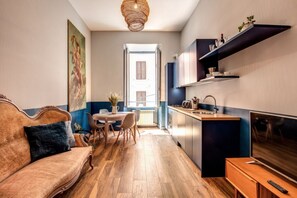 Un espacio habitable compacto con sofá, mesa de comedor y kitchenette.