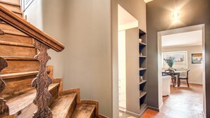Una escalera de madera que conduce a una sala de estar con una mesa de comedor y sillas.