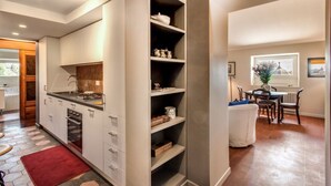 Una cocina moderna con armarios blancos, horno integrado y una alfombra roja.