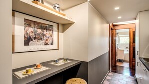 Una cocina moderna con encimera oscura, un taburete de madera y una obra de arte enmarcada sobre la encimera.