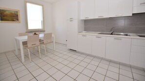 A modern kitchen with white cabinets, a tiled backsplash, and a window providing natural light. - Promenade, overlooking the Marciana Marina promenade (Marciana Marina)