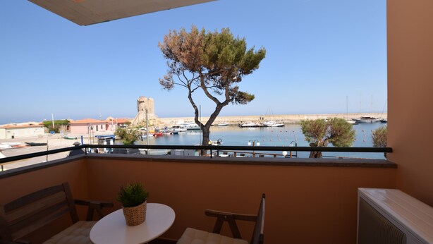 A balcony with a table and chairs, overlooking a marina with boats and a coastal town. - Promenade, overlooking the Marciana Marina promenade (Marciana Marina)