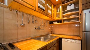 A kitchen with wooden cabinets, a stainless steel sink, a dishwasher, and a gas stove. - Apartments Cime (Dubrovnik)