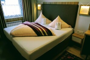 A neatly made bed with pillows and a blanket, a bedside table with a lamp, and a window with curtains. - Hotel Markterwirt (Altenmarkt im Pongau)