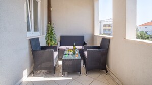 A balcony with wicker furniture, a glass table, and a potted plant. - Apartment Filip (Dubrovnik)