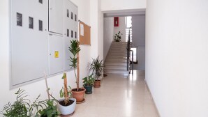 A hallway with potted plants, a staircase, and a bulletin board. - Apartment Filip (Dubrovnik)