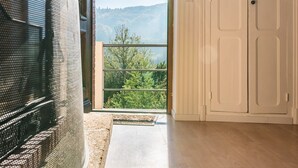 A room with a large window, a view of greenery, a white door, and a tiled floor. - Do you want to dream and relax? Welcome to the Morvan (Cussy-en-Morvan)