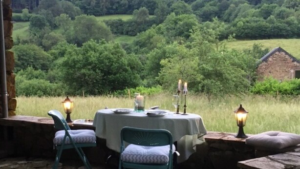 An outdoor dining area with stone walls, two chairs, a table with a tablecloth, and two lit lanterns. - Do you want to dream and relax? Welcome to the Morvan (Cussy-en-Morvan)