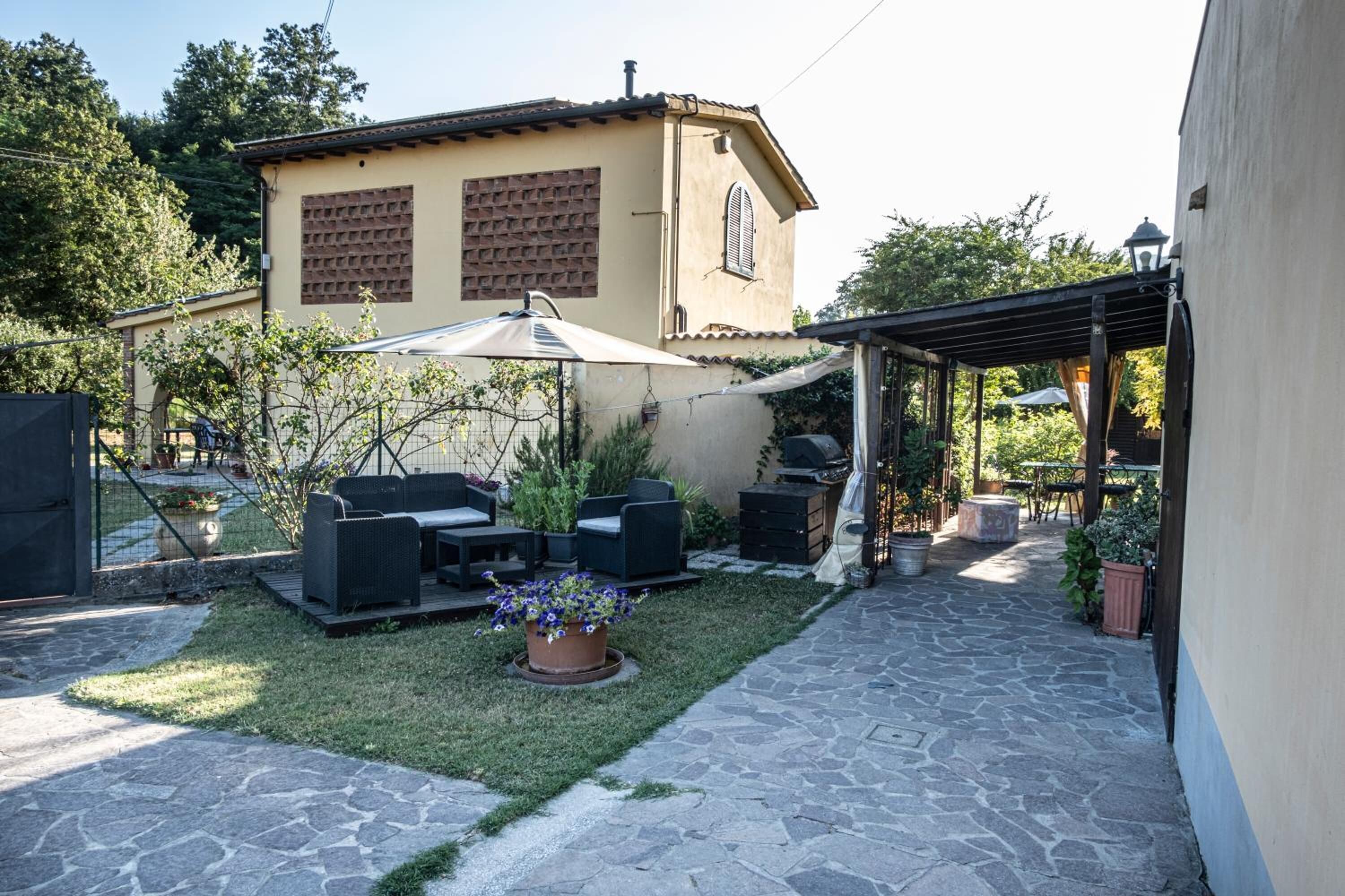 Un'area patio con mobili da esterno, una pergola e un vialetto in pietra.