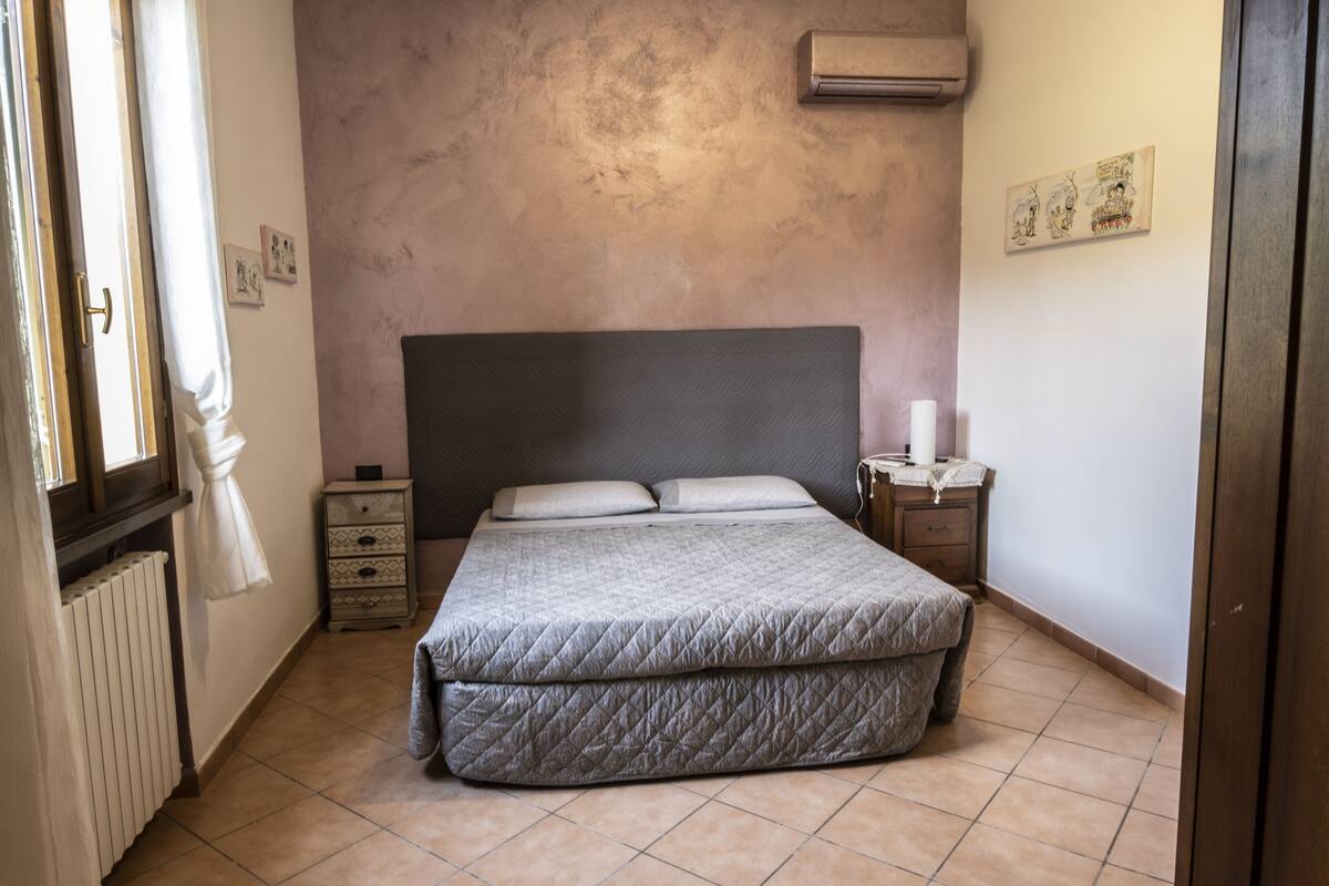Un dormitorio con una cama grande, un aparador, una mesita de noche y un radiador.