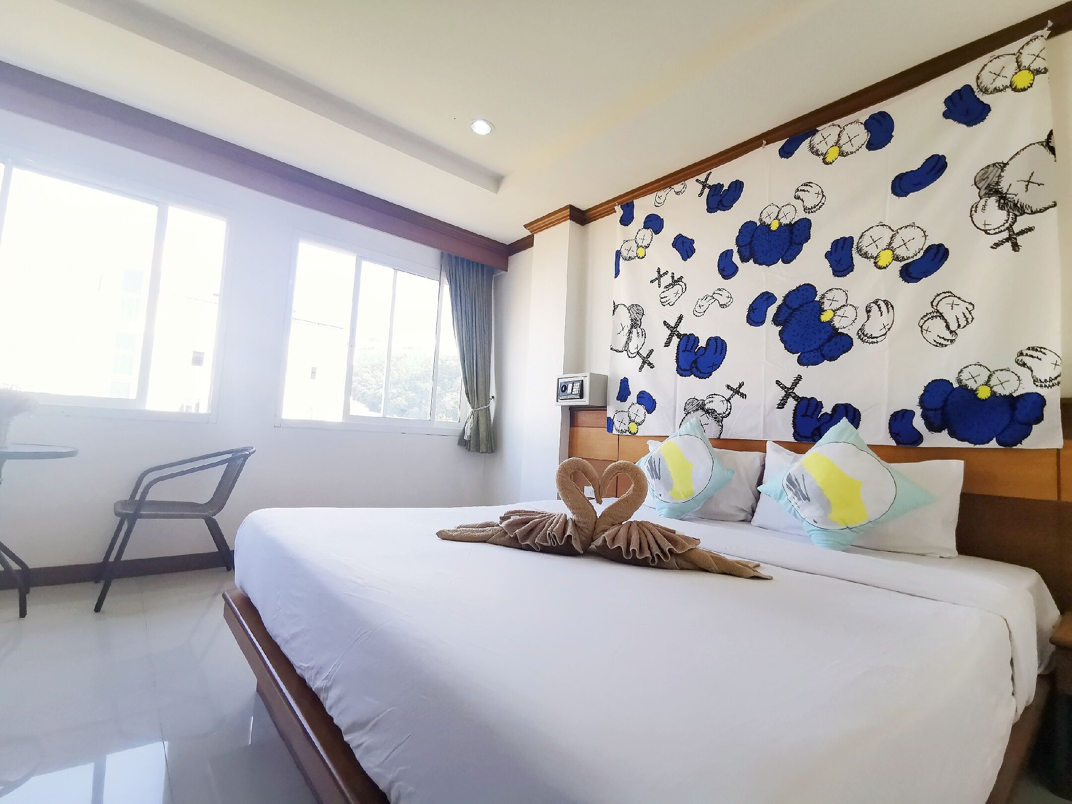 A hotel room with a large bed, a desk, and a window with curtains.