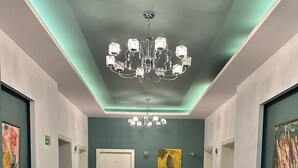 A hallway with a chandelier, green walls, and a potted plant. - ALBON Park (Berat)
